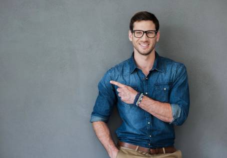 A man in blue shirt and brown pants pointing to his left.