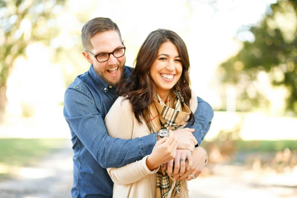 A man and woman hugging each other outside.