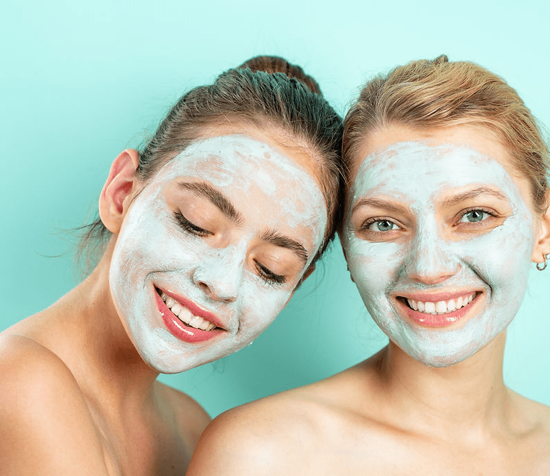 Two women with face masks on smiling for the camera.