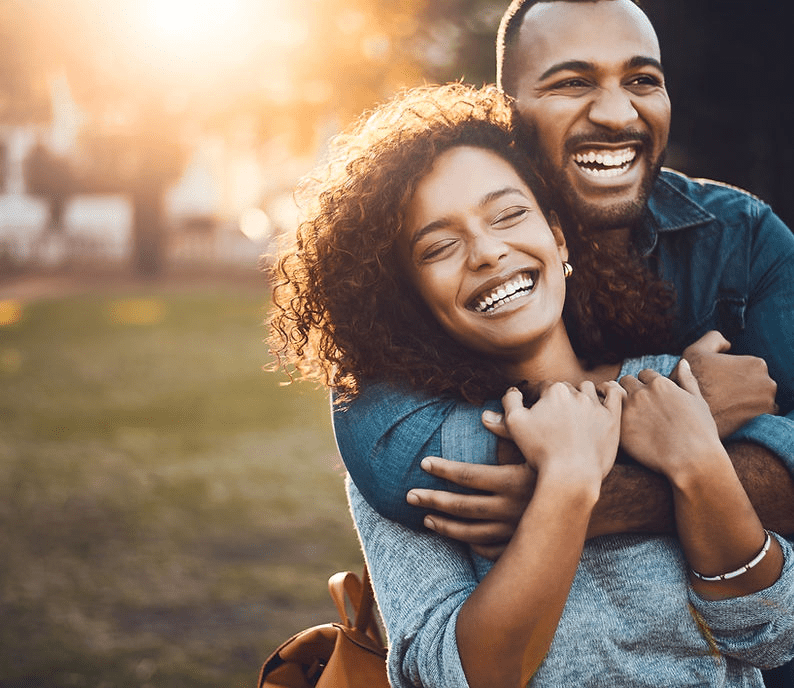 A man and woman hugging in the park.