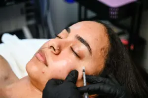 A woman getting her face painted with black gloves.