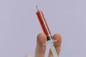 A person holding an empty syringe in their hand.