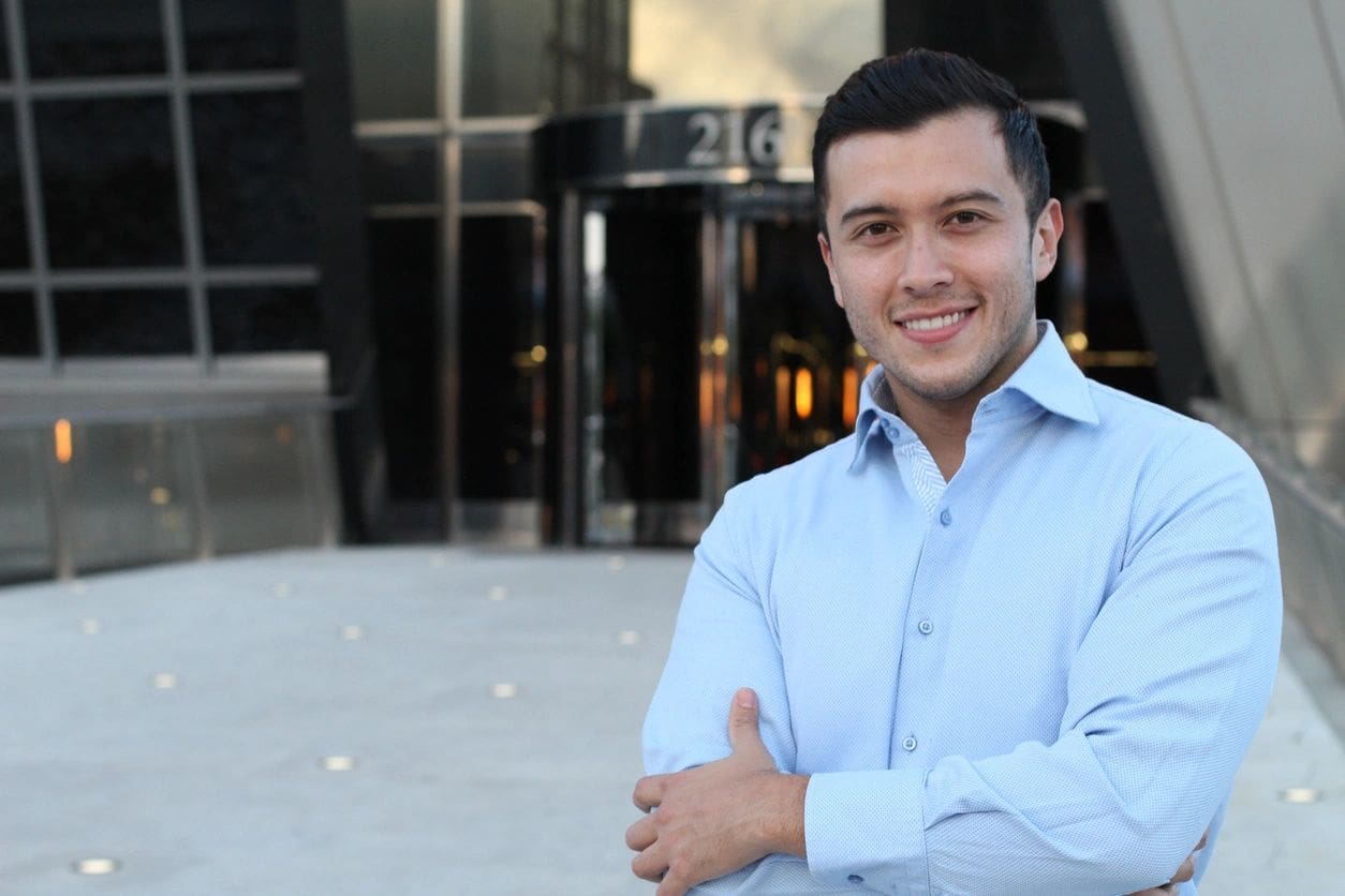 A man in blue shirt standing next to a building.