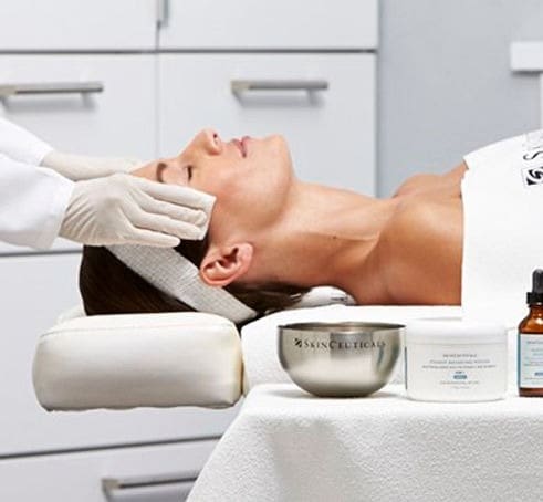 A woman getting her face cleaned by a doctor.