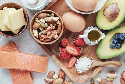 A wooden tray topped with eggs, nuts and strawberries.