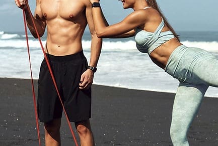 A man and woman are holding hands on the beach.