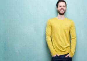 A man in yellow shirt leaning against wall.