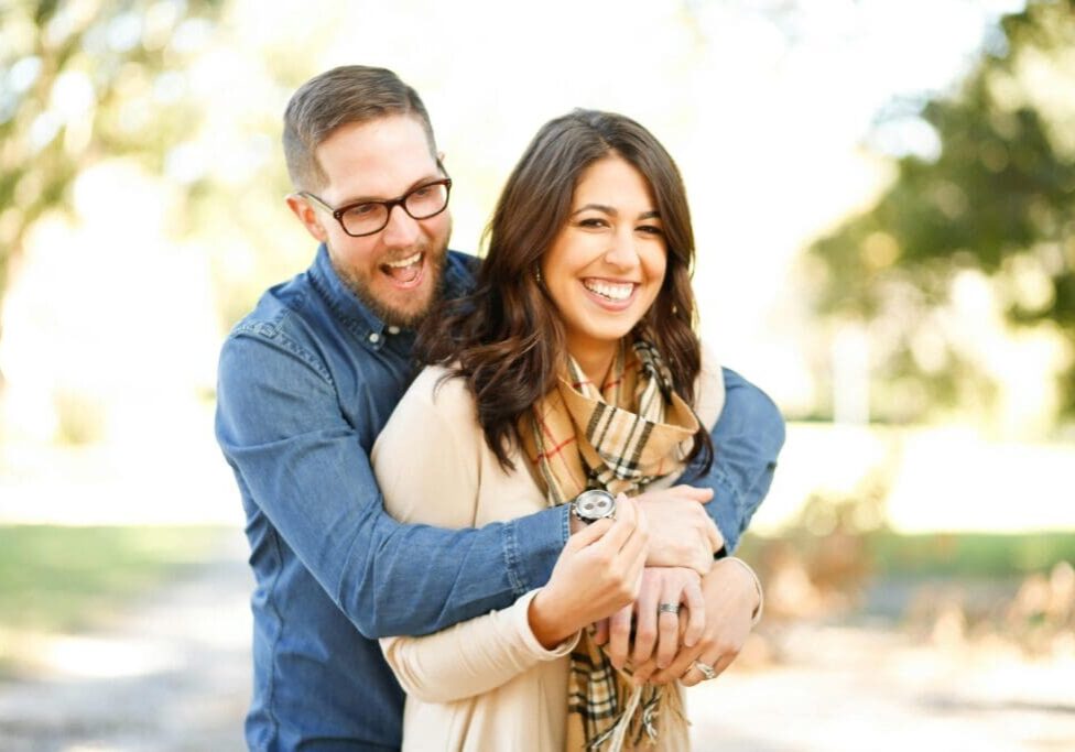 A man and woman hugging each other outside.